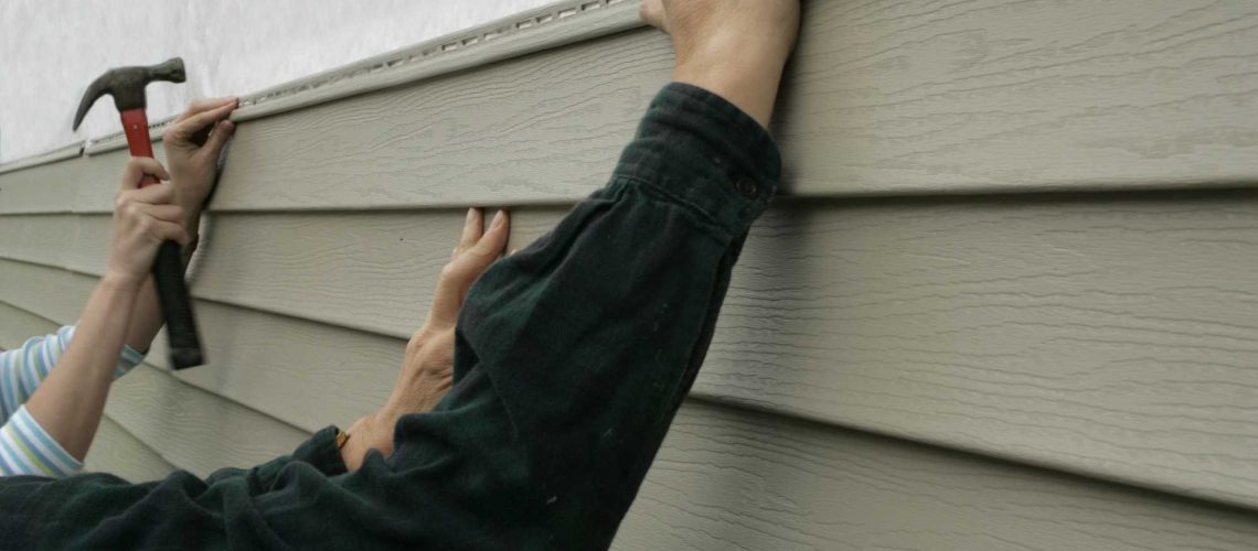 Workers installing siding on a house