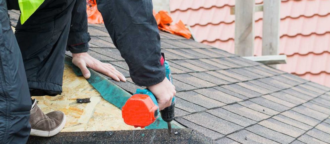 Roofer builder worker dismantling roof shingles